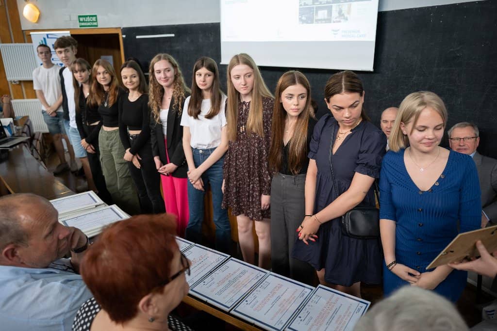 Uczniowie I LO stoją na scenie sali wykładowej szpitala wojewódzkiego w Poznaniu i odbierają wyróżnienia