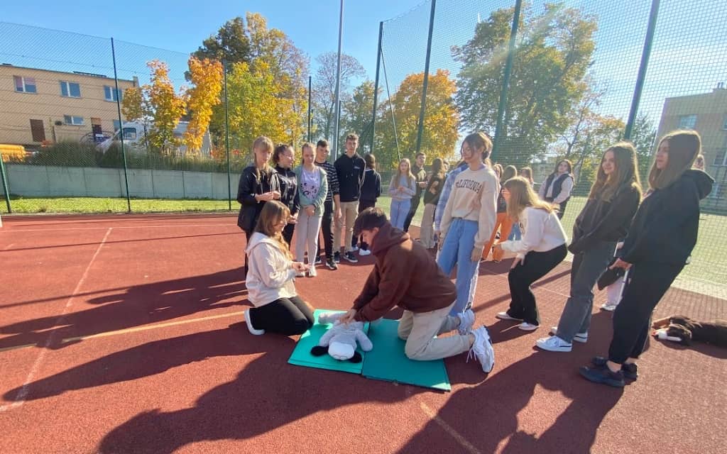 Na zdjęciu uczniowie na szkolnym boisku podczas treningu prowadzania resuscytacji krążeniowej.