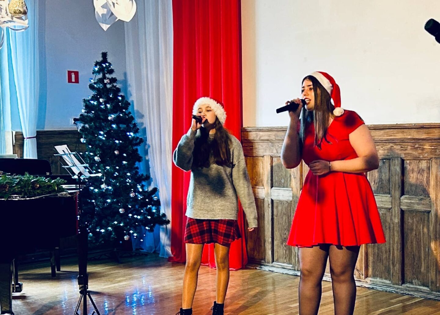 Za zdjęciu uczniowie na scenie w szkolnej auli wykonuje utwór podczas świątecznego koncertu.