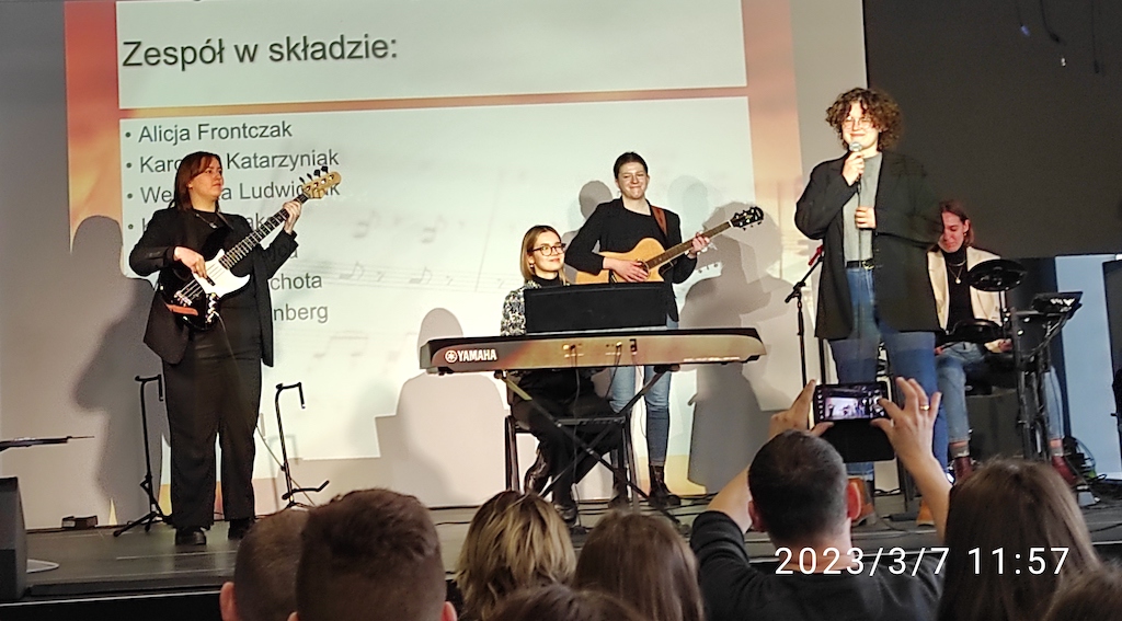 Na zdjęciu pięciu muzyków z instrumentami na scenie. W tle plakat Akademii Muzycznej w Poznaniu.