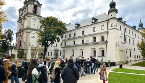 Grupa uczniów podczas krajoznawczej wycieczki w Krakowie. Na pierwszym planie przewodnik, a w tle historyczny kościół.