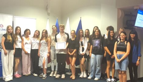 Na zdjęciu grupa uczniów i dwie nauczycielki. Uczniowie odbierają nagrodę specjalna za udział w Kampanii społecznej “Drugie życie” organizowanej przez Fresenius Medical Care.