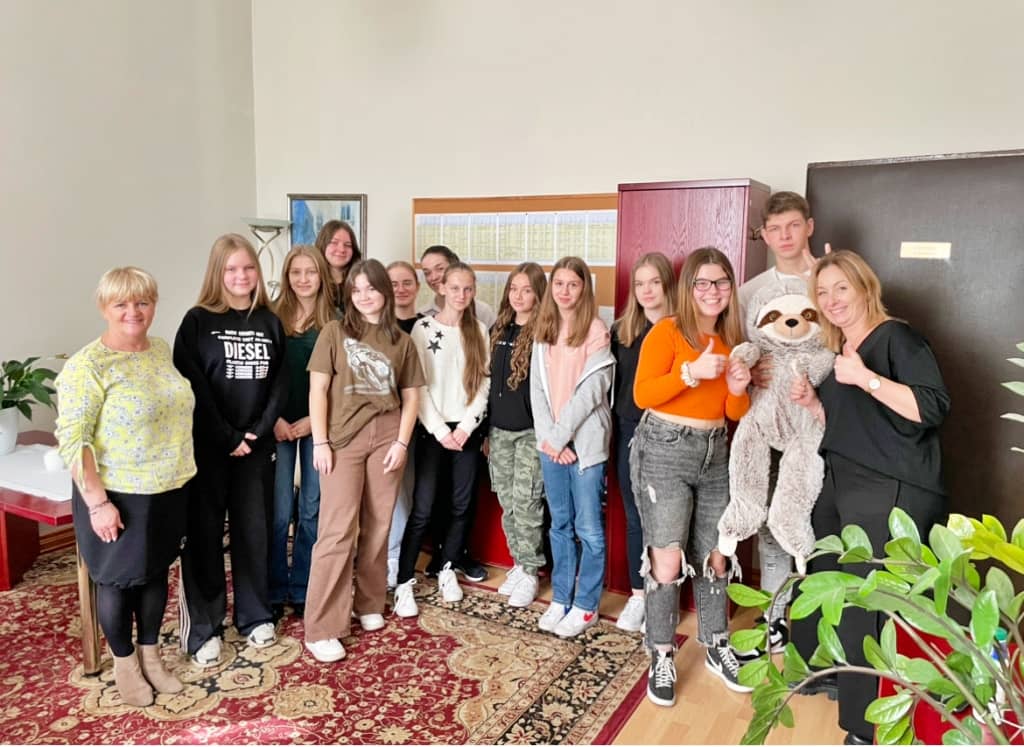 Na zdjęciu kilkunasto osobowa grupa uczniów wraz z dyrektorem szkoły. Uczniowie odbierają wyróżnienie w konkursie na najlepszy uśmiech.