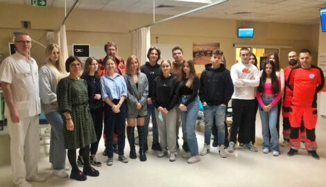 Na zdjęciu uczniowie wraz z opiekunem na zajęciach w Pleszewskim Centrum Medycznym. Osoby na zdjęciu stoją na tle medycznego sprzętu.