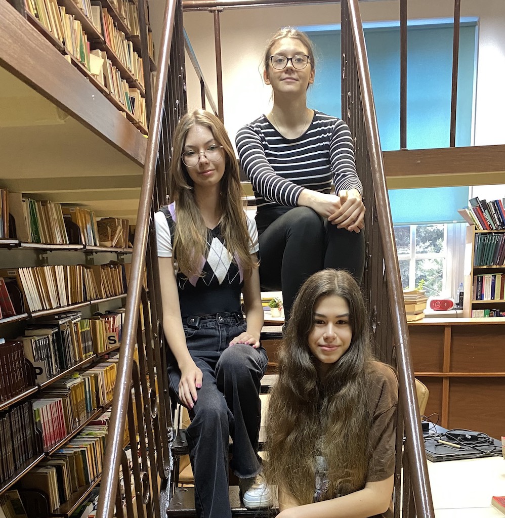 Na zdjęciu trzy uczennice w bibliotece. Uczennice są laureatkami Konkursu Przyrodniczego SALAMANDRA.